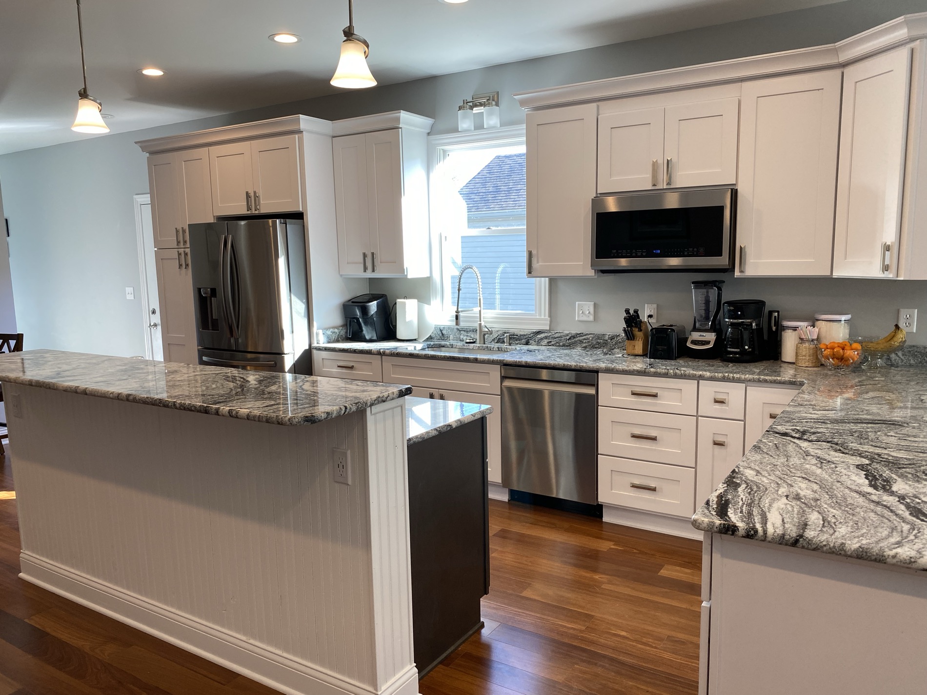 A custom granite kitchen with a dark island, fabricated and installed by Argent Concepts