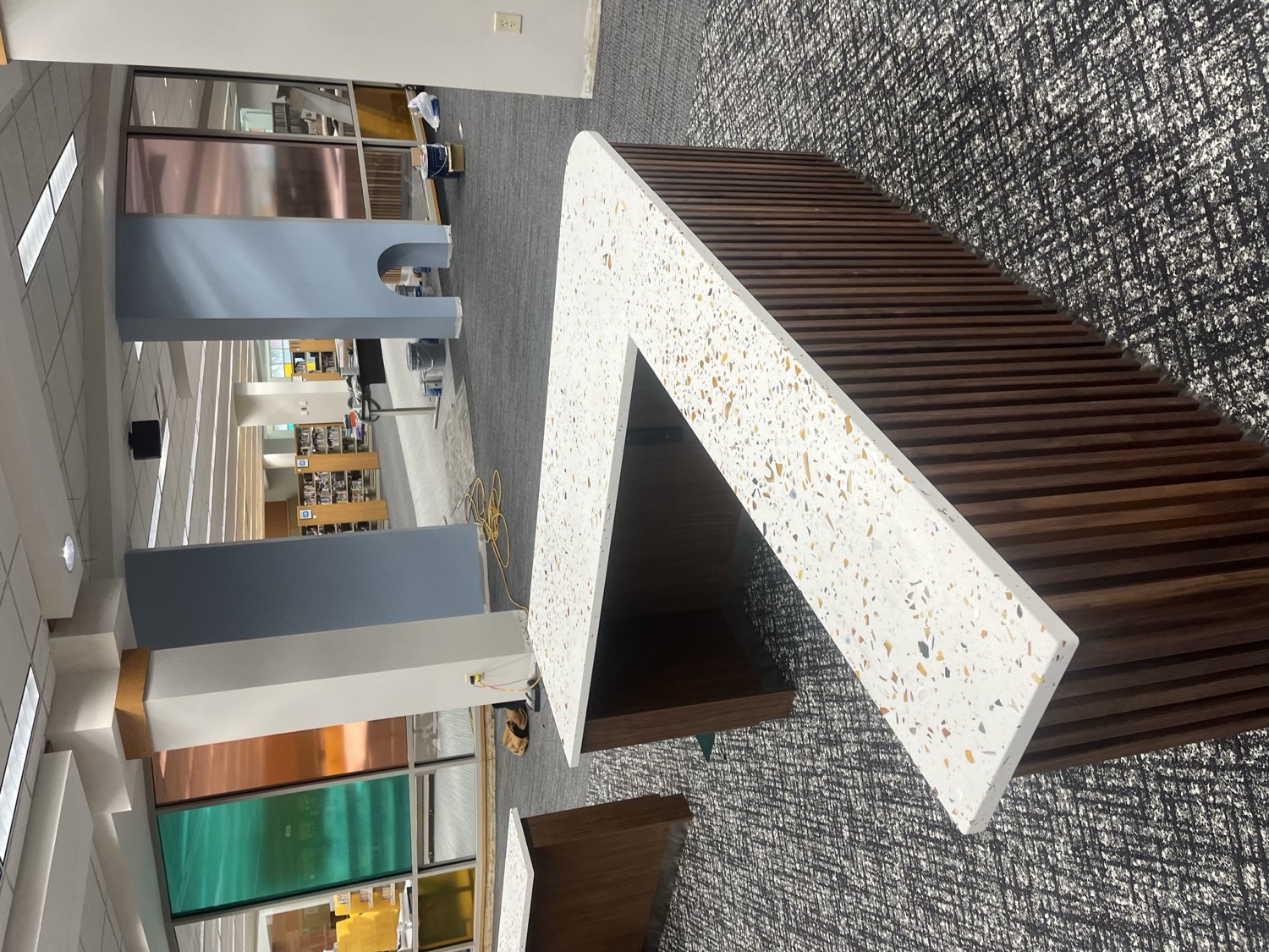 Terrazzo-look solid surface library circulation desk on a fluted wood base by Argent Concepts